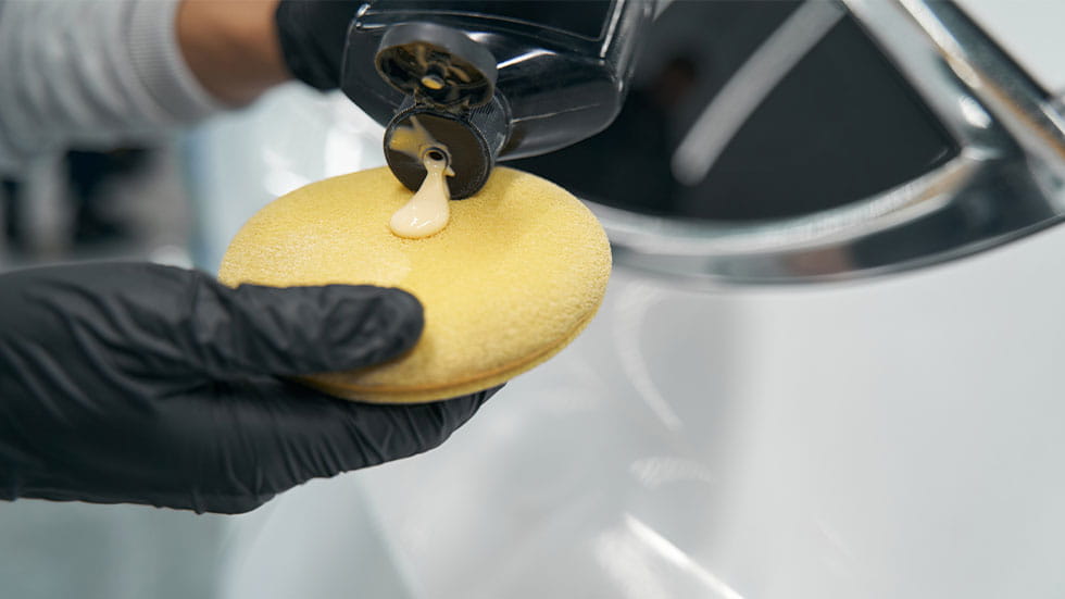 man putting car wax on sponge