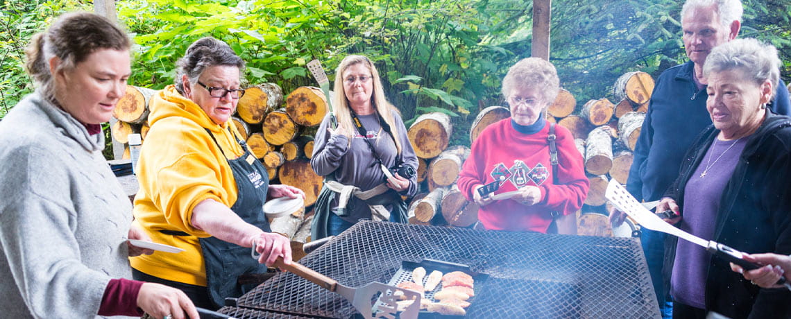 Group grilling salmon on open grill while in Alaska