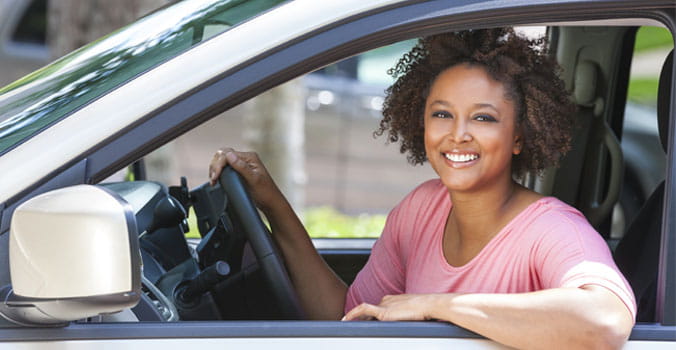 Woman sitting in driver's seat of car smiling