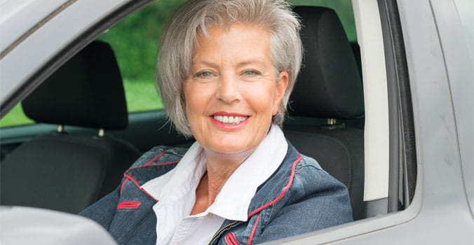 Older woman in drivers seat of car with window down