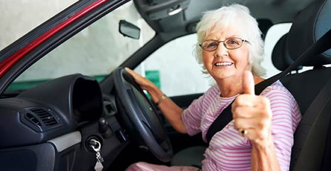 Senior lady in car giving thumbs up