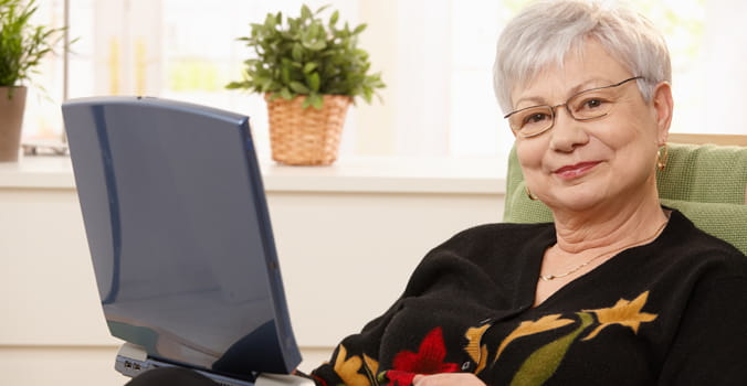 Older woman sitting at home with a laptop in her lap