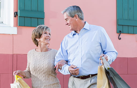 Older couple walking arm in arm with shopping bags