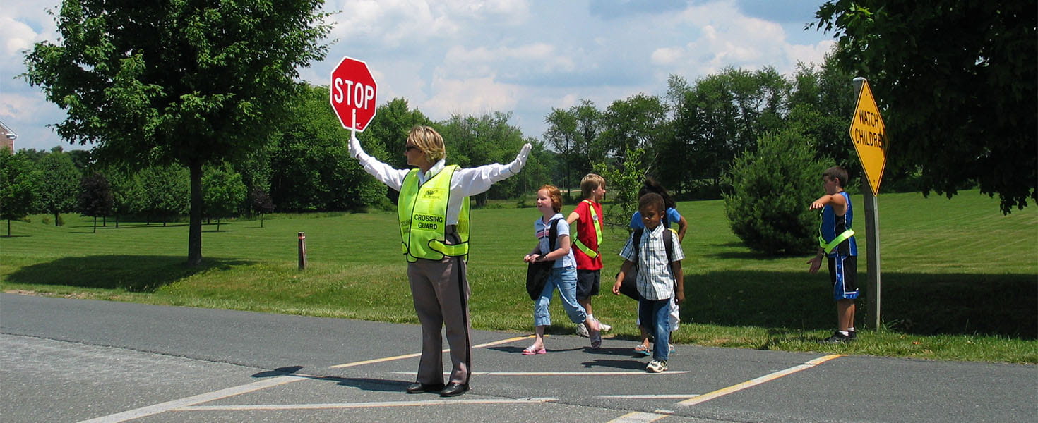 Crossing guard helps kids safety cross the street