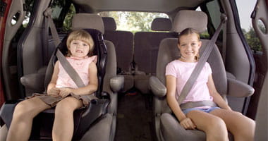 Two young girls seating in the back of a van