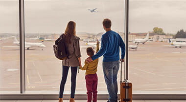 Family of three looking out the airport window