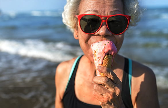 Older woman enjoying an ice cream cone on the beach