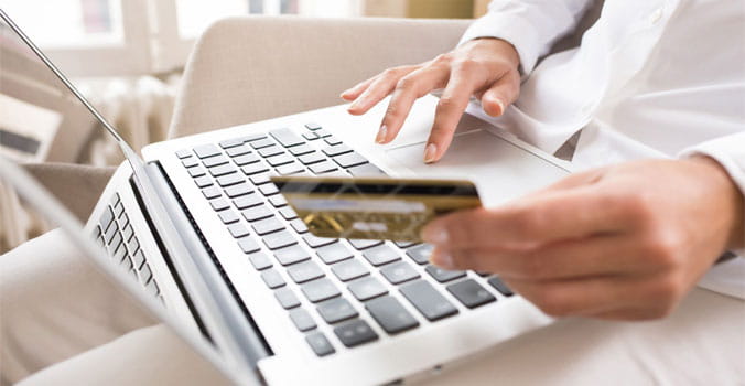 Woman with Laptop in Lap Holding a Credit Card