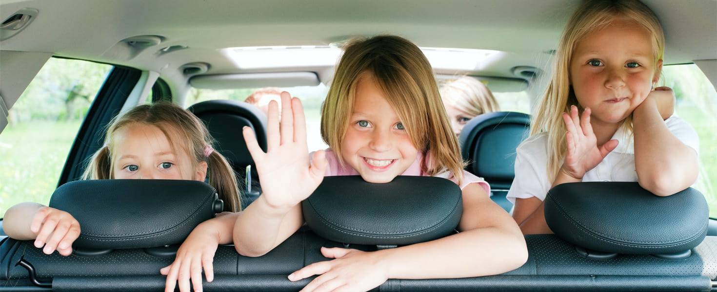 Children in back of car smiling.