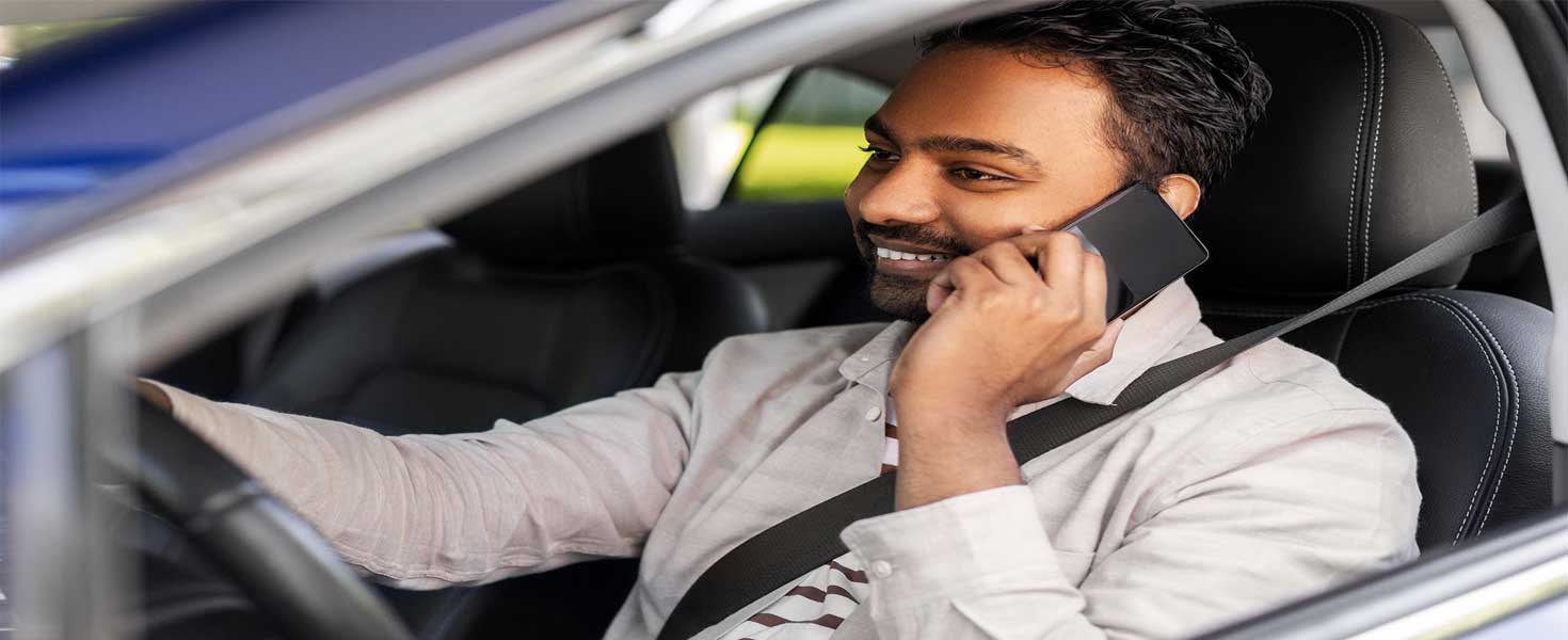 Indian man or driver driving car and calling on smartphone