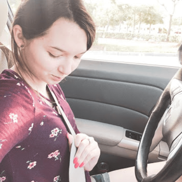 girl in car buckling her seatbelt