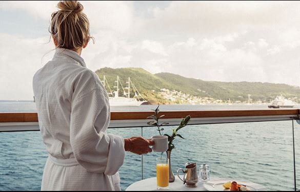 Cruise passenger relaxing in a robe with morning coffee, overlooking scenic view