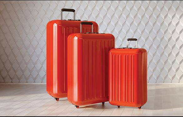 Three red suitcases sit atop a wood floor
