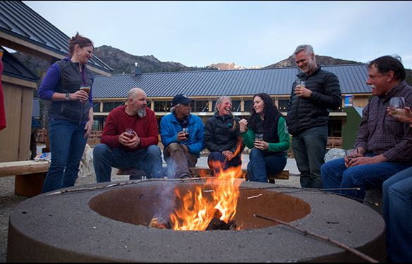 Guests smiling and socializing in front of fire pit at resort