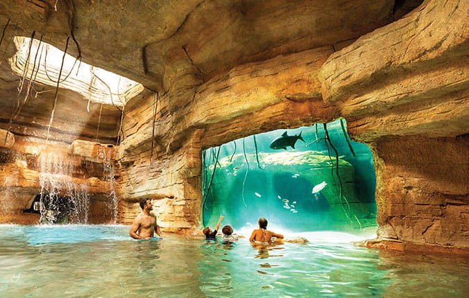 The Reef at Atlantis, visitors swimming in pool looking at fish tank