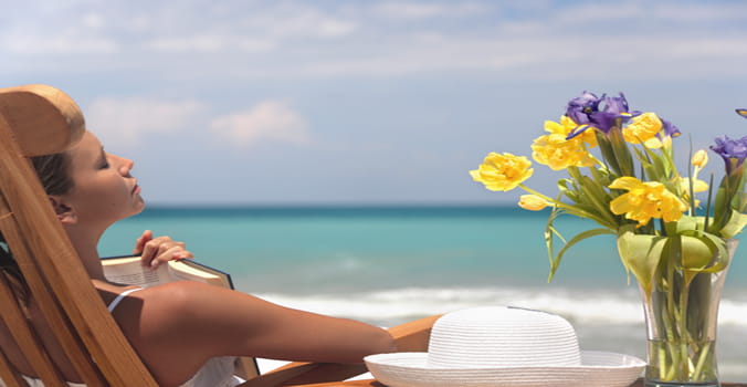 Woman relaxing with book on her chest on the beach