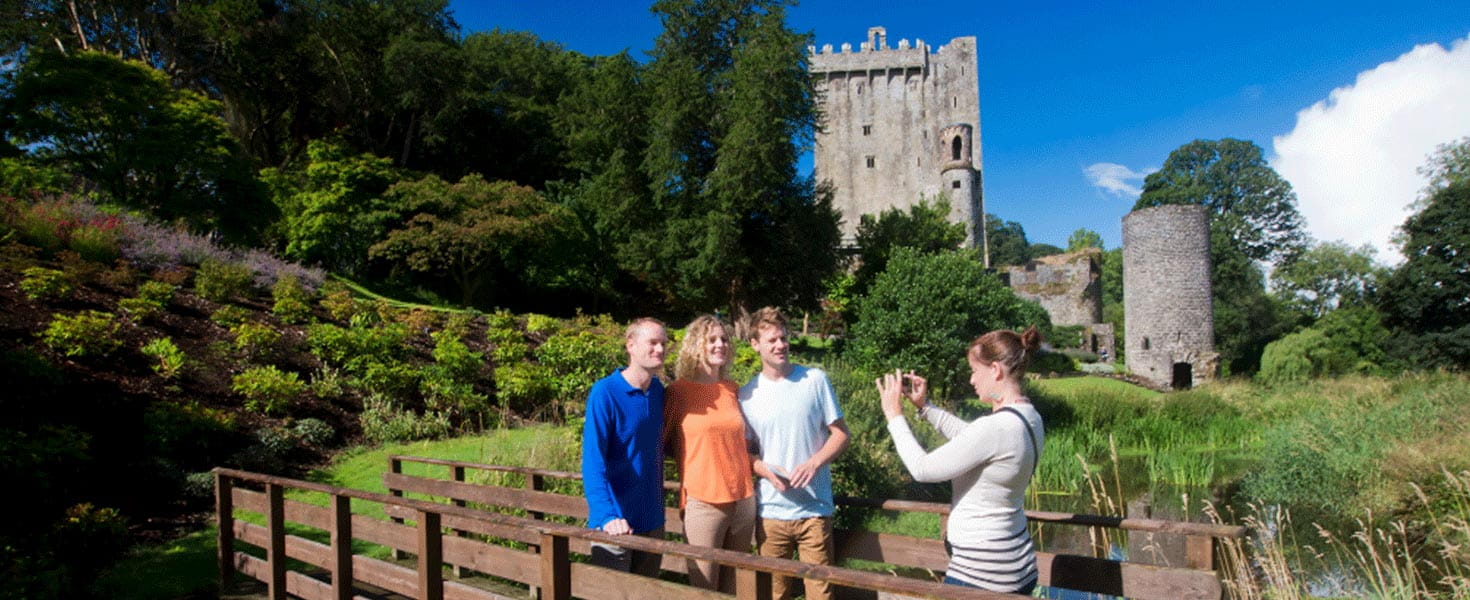 Tourists on bridge in front of Blarney Castle taking a photo