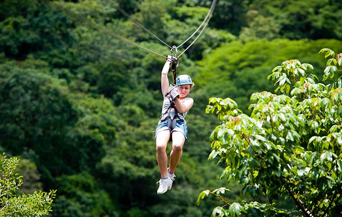 Girl zip lining through rain forest in Costa Rica