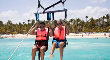 Happy couple Parasailing in Dominicana beach in summer.