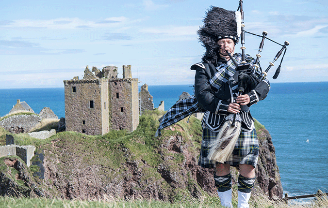 Bagpipe player in front of castle in Scotland