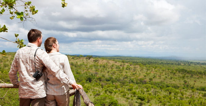Couple on safari vacation looking to savanna from balcony