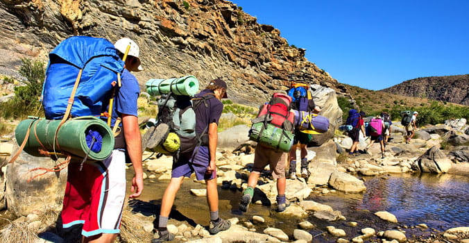 Hikers cross small river in the mountains of Western Cape, South Africa