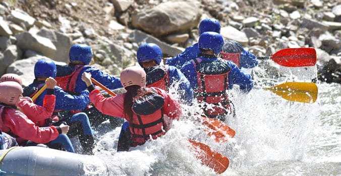Group of men and woman white water rafting