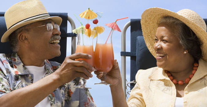 Retired couple saying cheers with their cocktails while on vacation