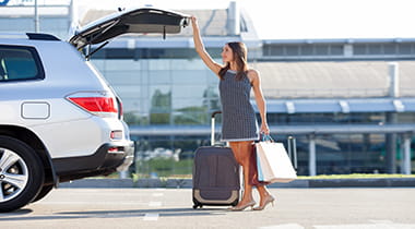 Woman getting luggage out of her trunk in a parking lot
