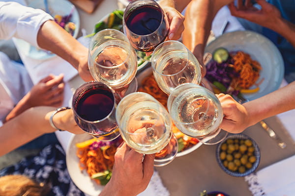 Group of friends having a meal outdoors. They are celebrating with a toast using wine.