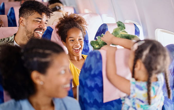 Family taking a trip on a plane. Girl is playing with toy dinosaur.