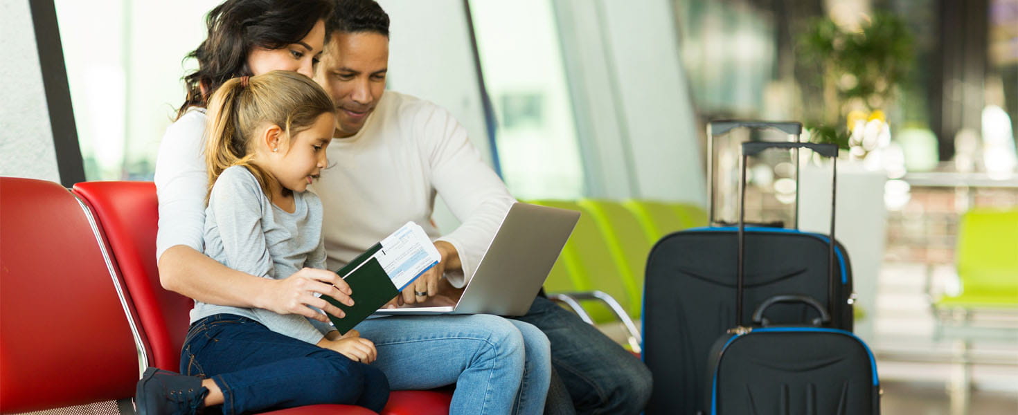 Parents and little daughter using laptop at airport