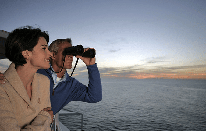 Couple with binoculars on the deck of a Regent Seven Seas cruise