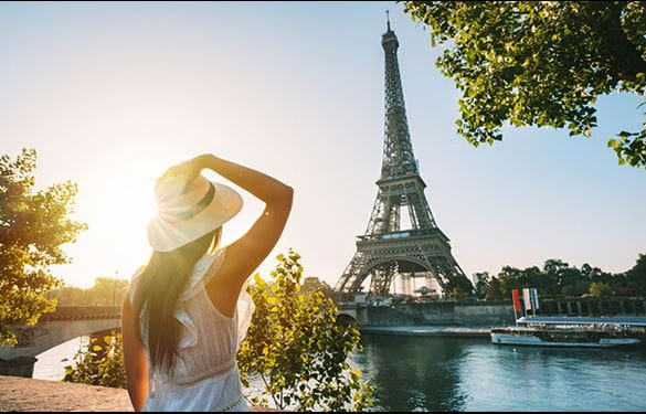 A woman in a hat, marveling at the beauty of the Eiffel Tower.