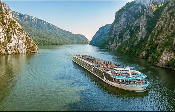 A cruise ship sailing peacefully along a river, surrounded by serene landscapes and clear blue skies.