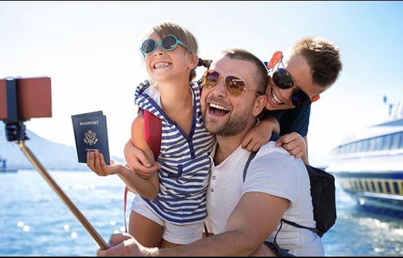 A man and two children capturing a moment with a boat in a selfie.