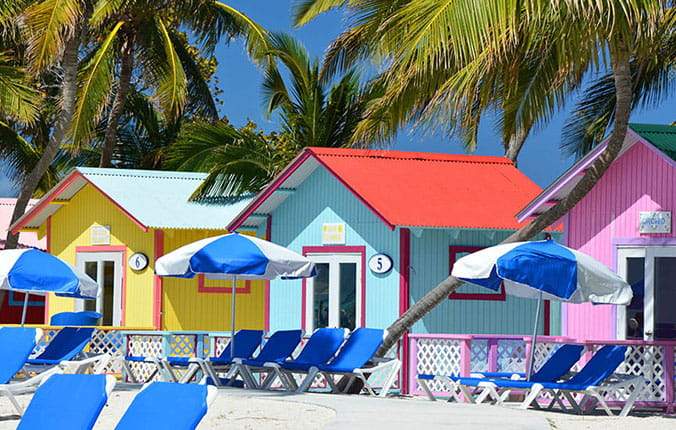 A vibrant row of beach huts adorned with umbrellas and chairs, creating a colorful and inviting seaside scene.