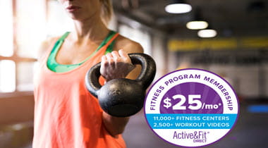 woman lifting kettle bell with gym blurred in background