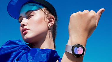 Woman wearing designer blue outfit and cap, showing smartwatch on wrist.