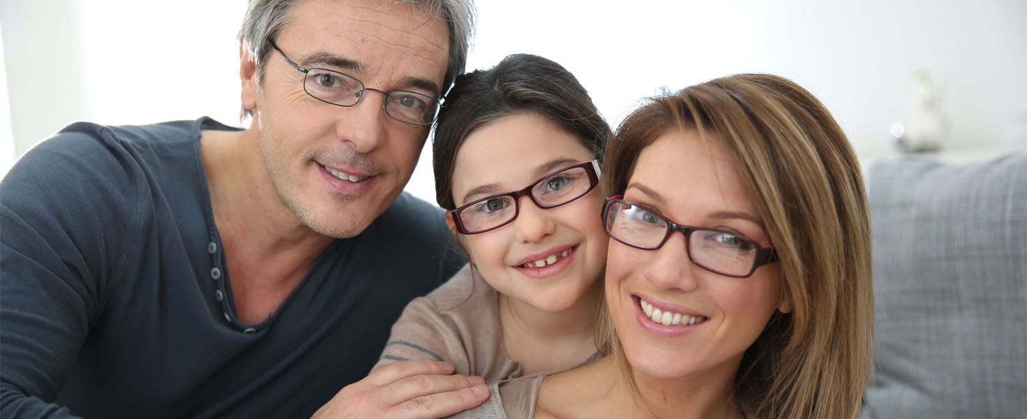 Family of three smiling wearing eyeglasses