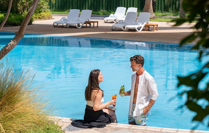 A couple enjoying drinks by the pool on a sunny day