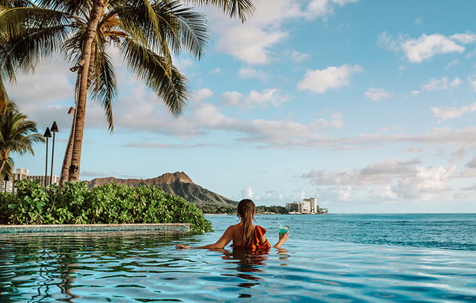Woman relaxes in a luxury resort infinity pool while enjoying a drink