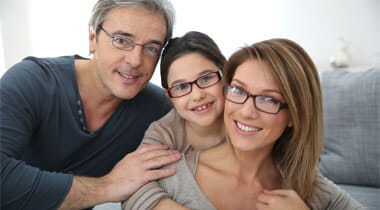 Family of three smiling wearing eyeglasses