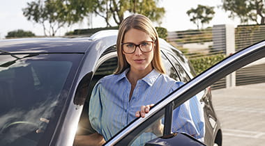 Woman in glass stands outside her car