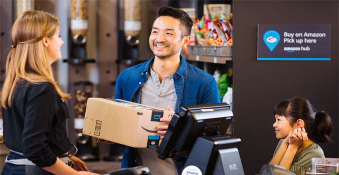 Man handing lady behind Amazon counter a package