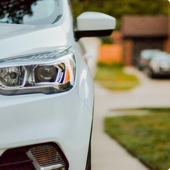 Close up view of a driver side headlight on a white sedan