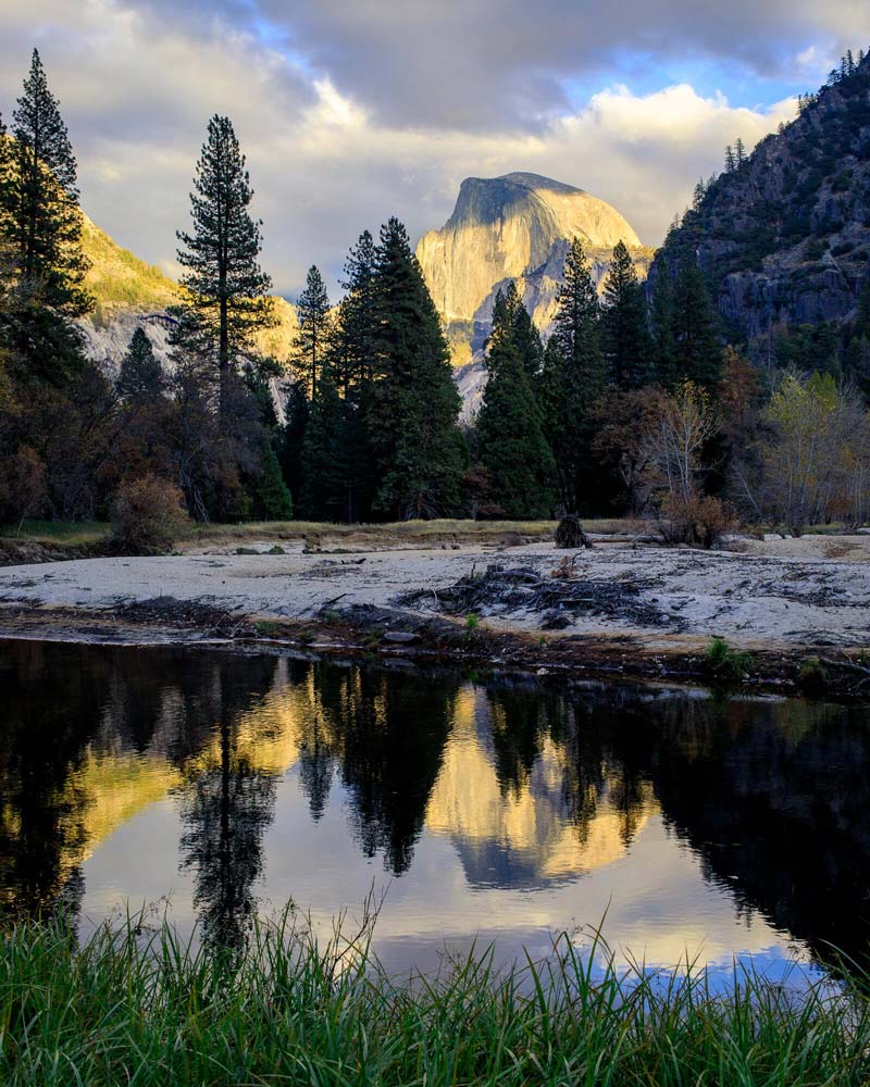 View of El Capitan in the distance, reflecting in water. 