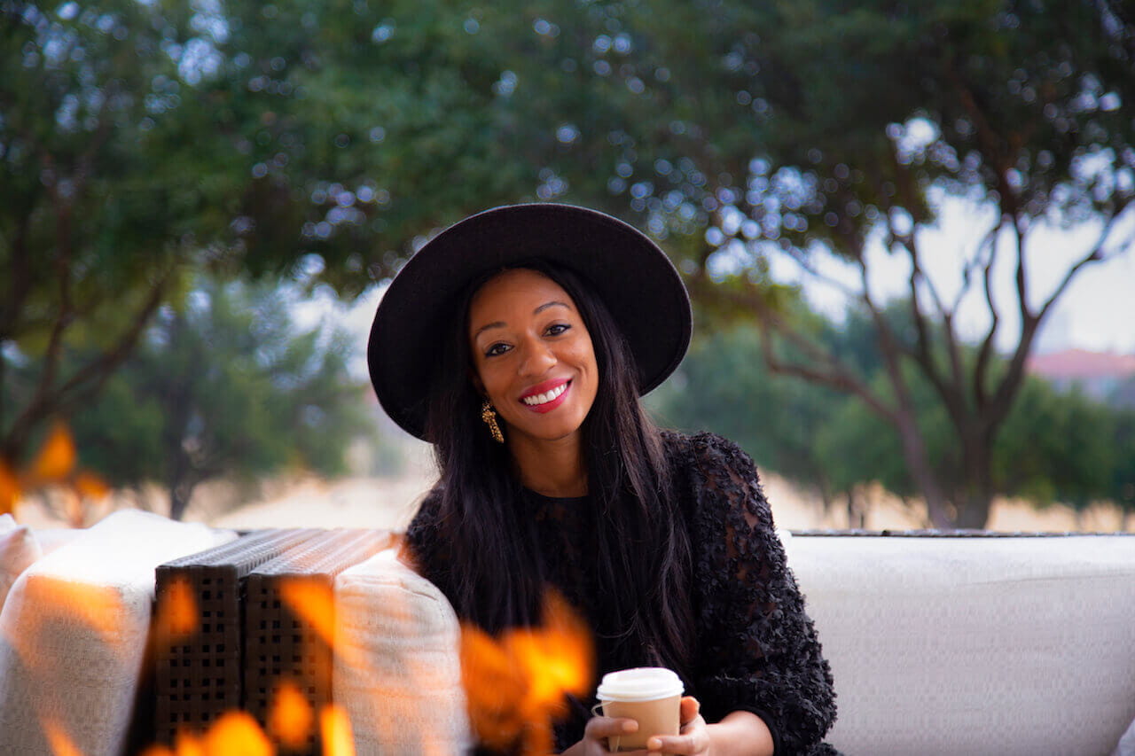 Author Adrienne Jordan sitting by a fire, drinking tea. 