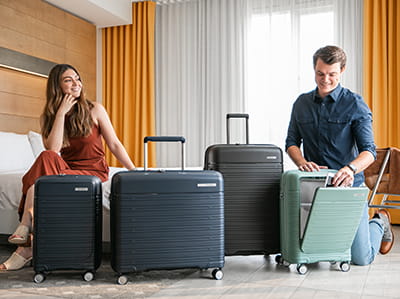 Couple in hotel room with a variety of Samsonite luggage.