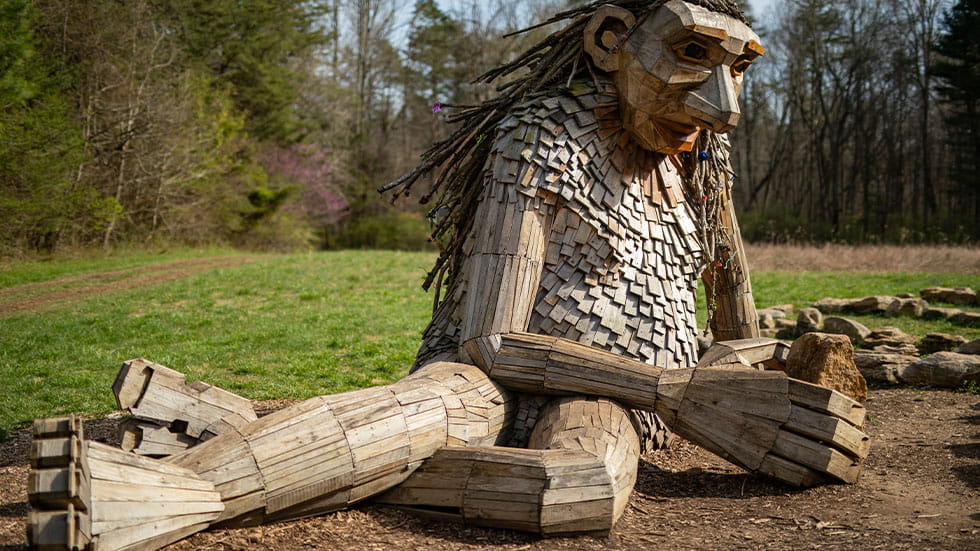 Giant wooden sculpture of a man sitting in Bernheim Arboretum and Research Forest